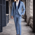 Man wearing a light blue three-piece suit with a white shirt and bow tie, walking confidently along a stone corridor.