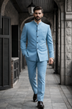 Man wearing a light blue bandhgala suit walking in a stone corridor.