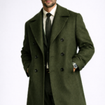 Man wearing a dark green double-breasted overcoat over a formal suit and tie, showcasing premium men's tailored outerwear.